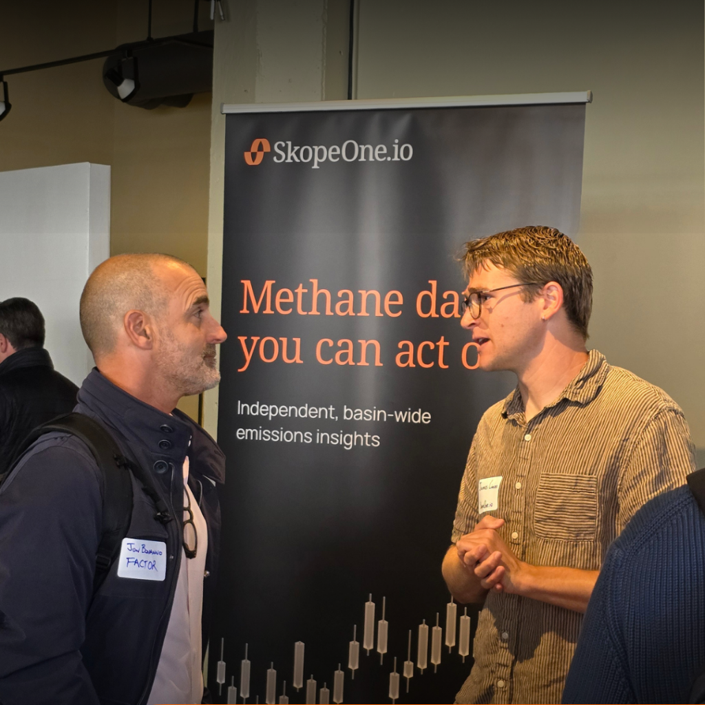 A member of the SkopeOne.io team talks with a booth visitor in front of a vertical banner at The Energy Summit held at SF Climate Week 2026